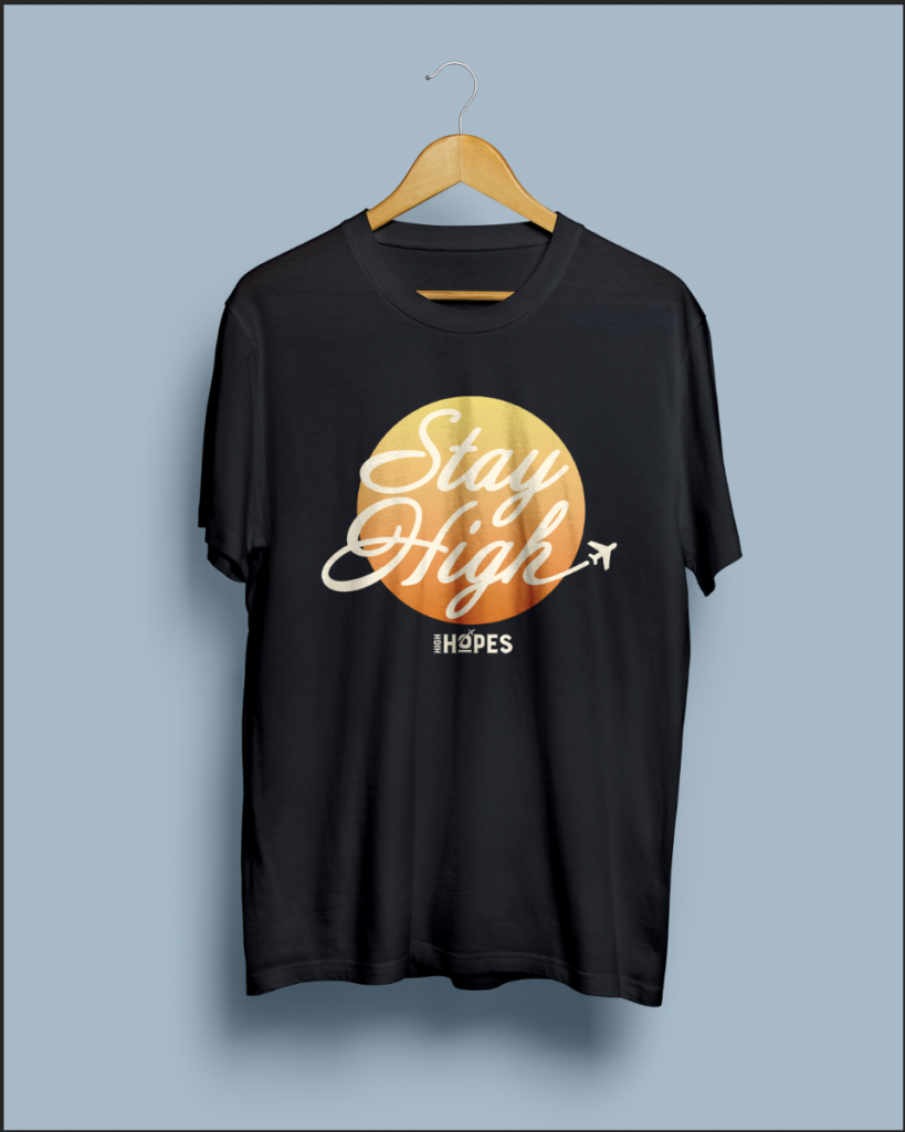 T-shirt for High Hopes cannabis dispensary: Black shirt with a gradient orange to yellow sun in the center. Text over the sun reads Stay High, and the High Hopes logo is underneath